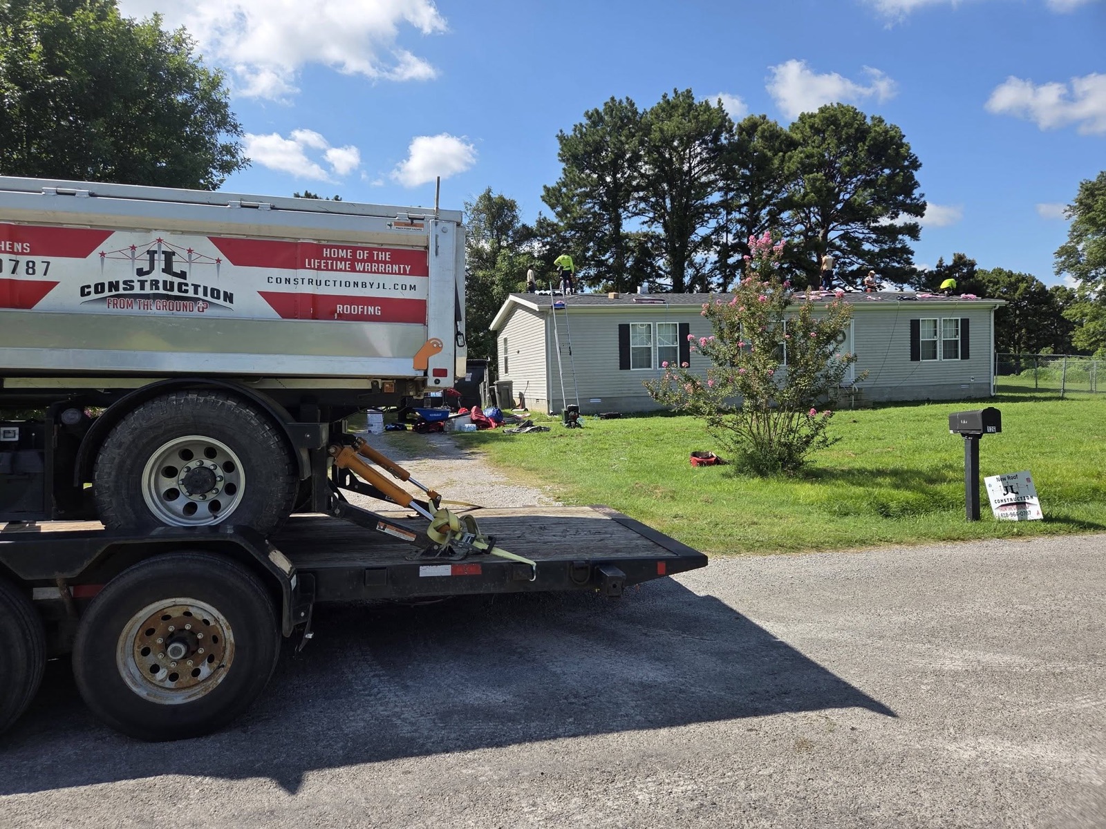 JL Construction truck and crew working on a roof job site